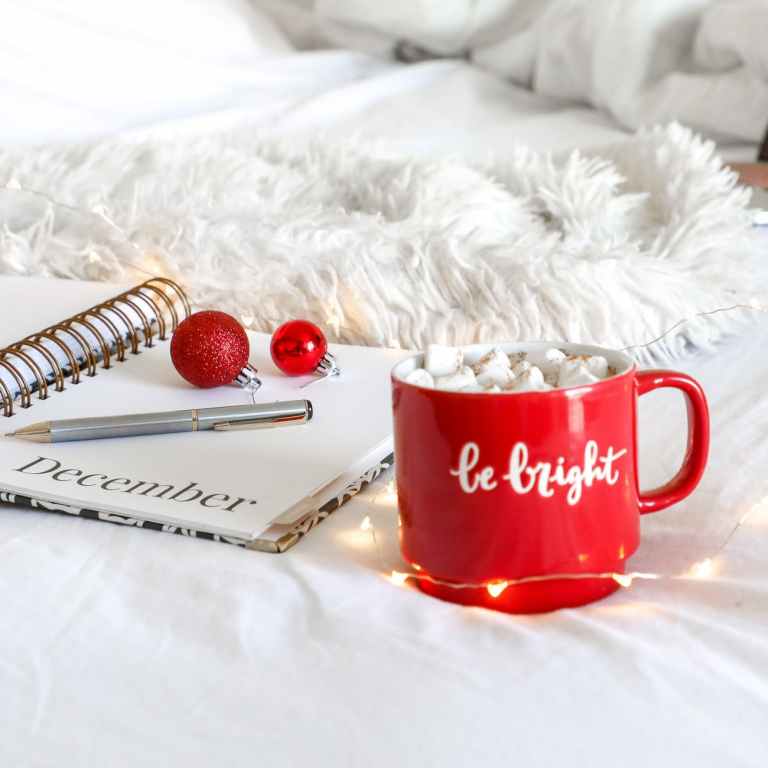 red ceramic mug on white mat beside notebook